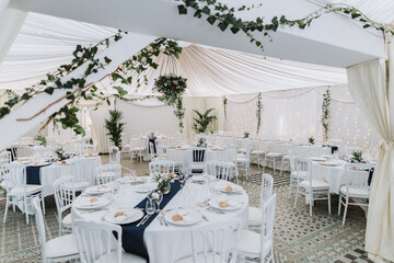 Wedding marquee with fairy lights, floral chandelier and elegant table settings at dusk