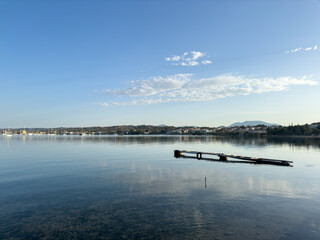 Old wooden pier remains with calm sea and anchored sailboats in Porto Cheli Greece under clear blue...