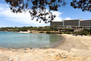Seaside hotel overlooking turquoise waters and sandy beach in Porto Cheli Greece under bright...