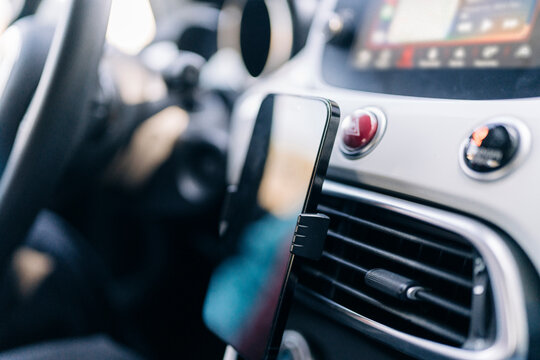 A smartphone is mounted in a car's air vent, integrated into the vehicle's dashboard. This setup provides convenient access for navigation or hands-free use while driving.