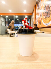 Disposable Coffee Cup on a Wooden Table in a Cafe