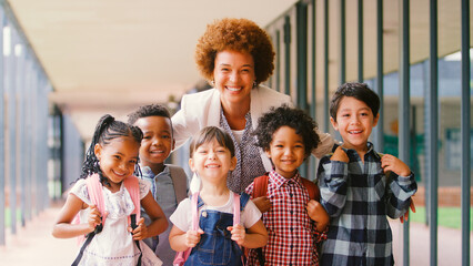 Portrait Of Smiling Multi-Cultural Elementary School Pupils With Female Teacher Outdoors At School