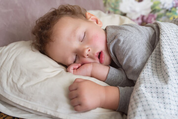 A curly child is sleeping in the bed
