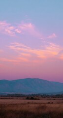 Pastel sunset over mountain range, vast field