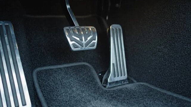 Close Up of Car Interior Featuring Metallic Pedals and Black Carpet Flooring