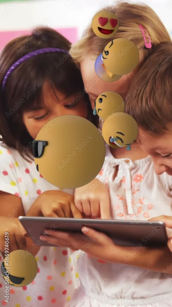 Aufkleber animation of emoticons floating over diverse children laughing and using digital tablet in classroom