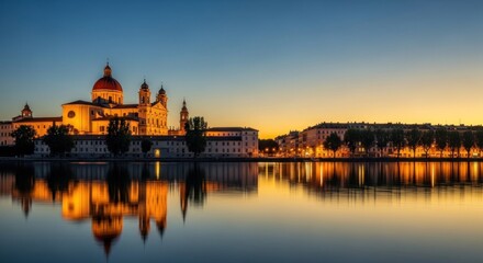Fototapeta premium Illuminated cathedral reflecting in calm water at dusk, showcasing architectural beauty.