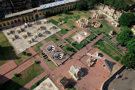 Aerial view of the Jantar Mantar's geometric forms in the muted sunlight, casting soft shadows across the red-bricked landscape, Jaipur, Rajasthan, India.