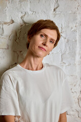 Mature woman in white shirt with calm thoughtful emotion. Concept of experience, wisdom, self-care, confidence, authenticity, lifestyle and aging gracefully.