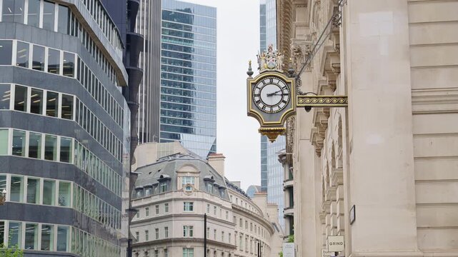 Close-up of a decorative white and gold clock mounted on a historic stone building in London, England