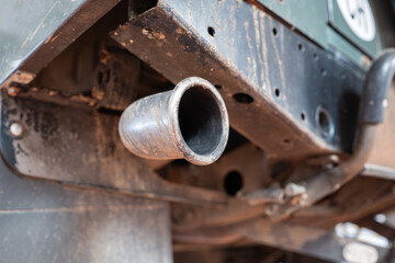 Car single exhaust muffler pipe and tip on a lifted car inside repair shop. Close up, wide angle,...