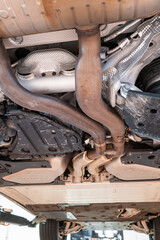 Car undercarriage with exhaust system, wheels and axel components. Wide angle, looking up view, car...