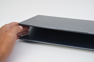 Hand closing slim modern laptop on white desk, concept of portable technology, digital work, and...