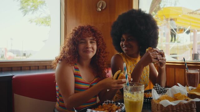 Multiethnic group of friends having meal at 80s vintage diner restaurant - Multicolored young people bonding and having fun, eating in an american fast food burger house	
