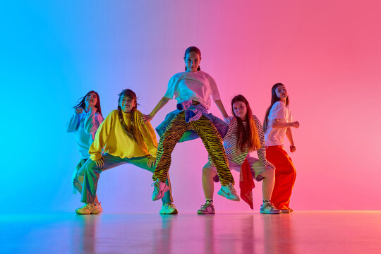 Youthful dancers pose under vibrant lighting, showcasing team spirit and urban dance creativity. Concept of modern dance expression and youth collaboration.