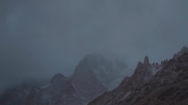 Dark clouds above the snowy Himalayan mountain peaks during a winter storm as seen from near Gonbo Rangjon mountain in Zanskar Valley, Ladakh, India. Slight snow on the mountain peaks due to storm.