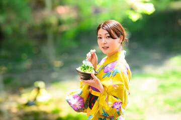 高原の湖で浴衣を着た女性がかき氷を食べている