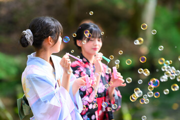 浴衣を着た日本人の小学生の女の子がシャボン玉で遊ぶ夏の風景