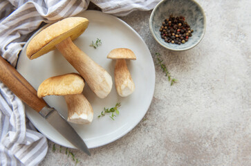 Fresh porcini mushrooms on plate with knife and peppercorns ready for cooking