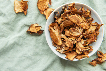 Dried mushrooms in a bowl resting on a green cloth