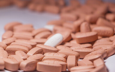 A Detailed Close-up of a Human Hand Delicately Selecting a Single Pill from a Large. Hand selecting or holding a single pill from a pile of different colored pills.