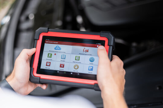 Modern technology in auto repair – mechanic using electronic car diagnostic tool. Mechanic using a digital diagnostic scanner to check car systems inside the vehicle. - Powered by Adobe