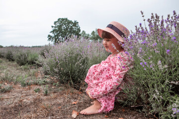Beautiful little girl child enjoying the scent of flowers, nature and relaxation while sitting in a...