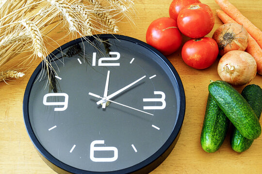 Work-life balance concept: time management for healthy home cooking with fresh vegetables and clock on kitchen counter. Balancing career and nutritious meal preparation. Remote worker wellness routine