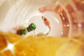 Man pouring beer from bottle into glass with joyful smile, view from inside. Concept of lifestyle content, menu and packaging, bar merch, advertising campaigns, branding, and social media promotion.