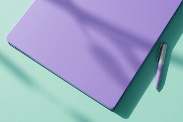 Minimalist purple notebook and pen on a mint green background with shadow