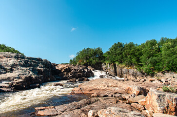 Naklejka premium streams of clear waterfall water and stone banks of a mountain river
