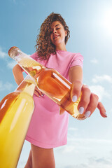 Woman in pink dress clicking beer bottle with confident smile outdoors. Concept of lifestyle...