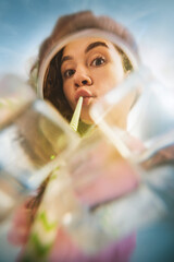Young woman drinking through straw with curious look inside glass with ice. Concept of lifestyle...