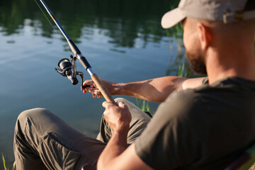Fisherman with rod fishing near lake at summer, selective focus