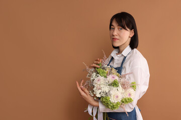 Florist with beautiful bouquet of flowers on dark beige background, space for text