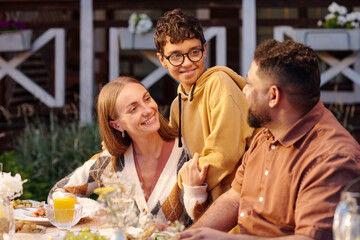 Caucasian woman, Middle Eastern man, and teenage boy interacting at outdoor table, teenage boy...