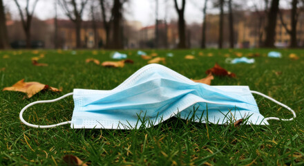 Lost Protection Mask on Grass in Fall Park Reflects Pandemics Impact.