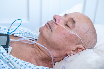 elderly man with sleep apnea monitoring device and fingertip pulse oximeter, senior male patient...