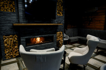 Cozy living room with a modern stone fireplace, warm flames flickering inside, creating an inviting and tranquil atmosphere.