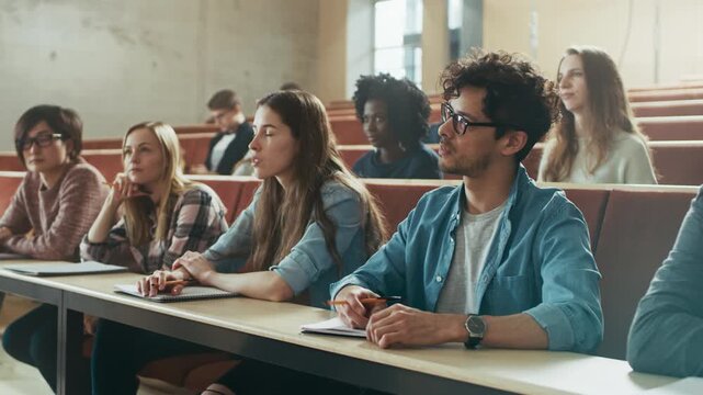 College Students Sit in a Lecture Hall, Listening, Taking Notes in University Class. Ambitios Young People Work on Getting Higher Education and Entering Workfoce as Productive Members of Society