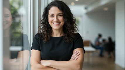 Confident and successful businesswoman with curly hair smiling with arms crossed in a modern office setting - Powered by Adobe