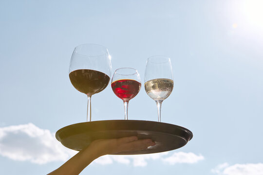 Red white and rose wine glasses on tray against blue sky. Concept of alcohol tourism, event promotion, festivals, lifestyle visuals, social media and modern hospitality branding.