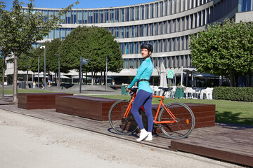 Sporty young woman riding bicycle on the road with protective helmet, symbol of healthy lifestyle...