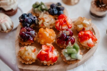 Close-up of assorted colorful fruit tarts on a wooden platter, showcasing vibrant fruits and berries