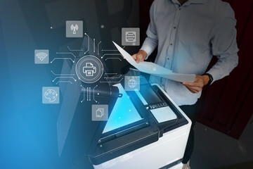 Man operates a multifunction printer in a modern office environment while using technology for document management