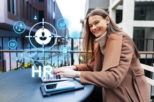 Professional woman working on laptop outdoors with HR icons displayed, showcasing modern recruitment technology