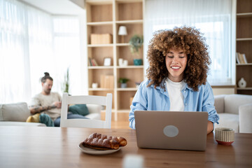 Smiling freelancer working from home on laptop at the table