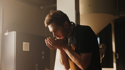 Bearded Caucasian male in professional clothing leaning forward in coffee factory. Holding fresh...