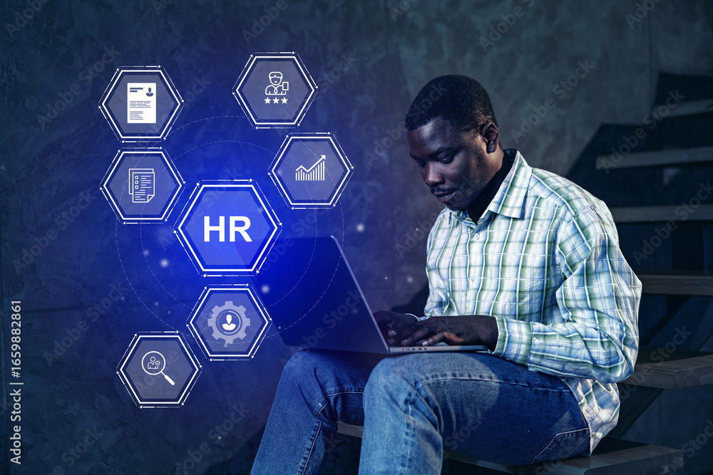 Poster working on human resources tasks with digital tools in a modern workspace during evening hours