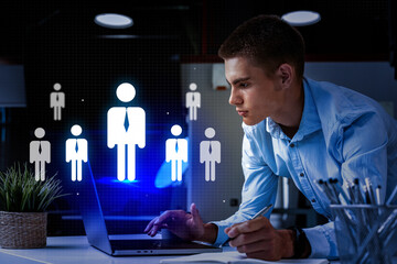 Business professional analyzing data on laptop with digital figures representing team members at office